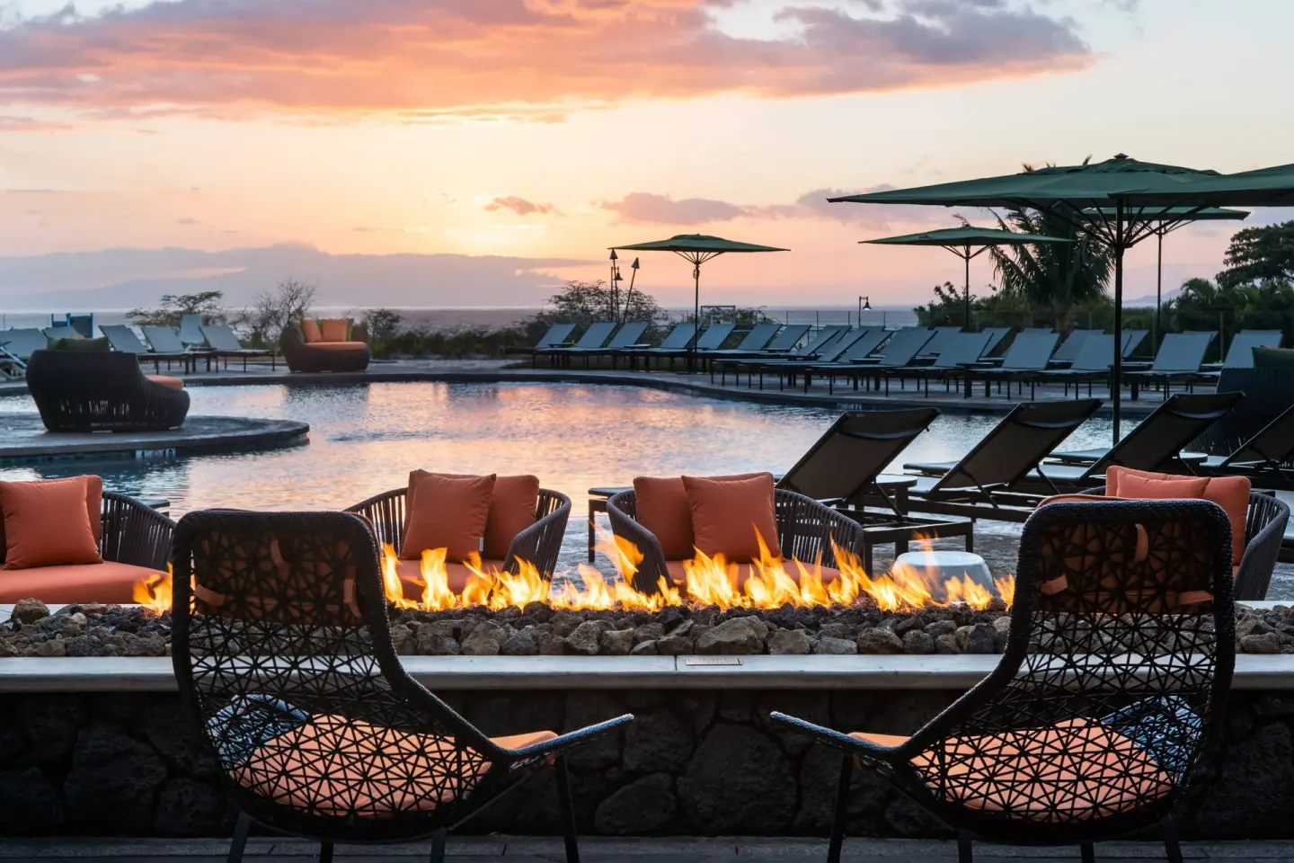 Poolside fire pit with lounge chairs at sunset at Residence Inn Maui Wailea.