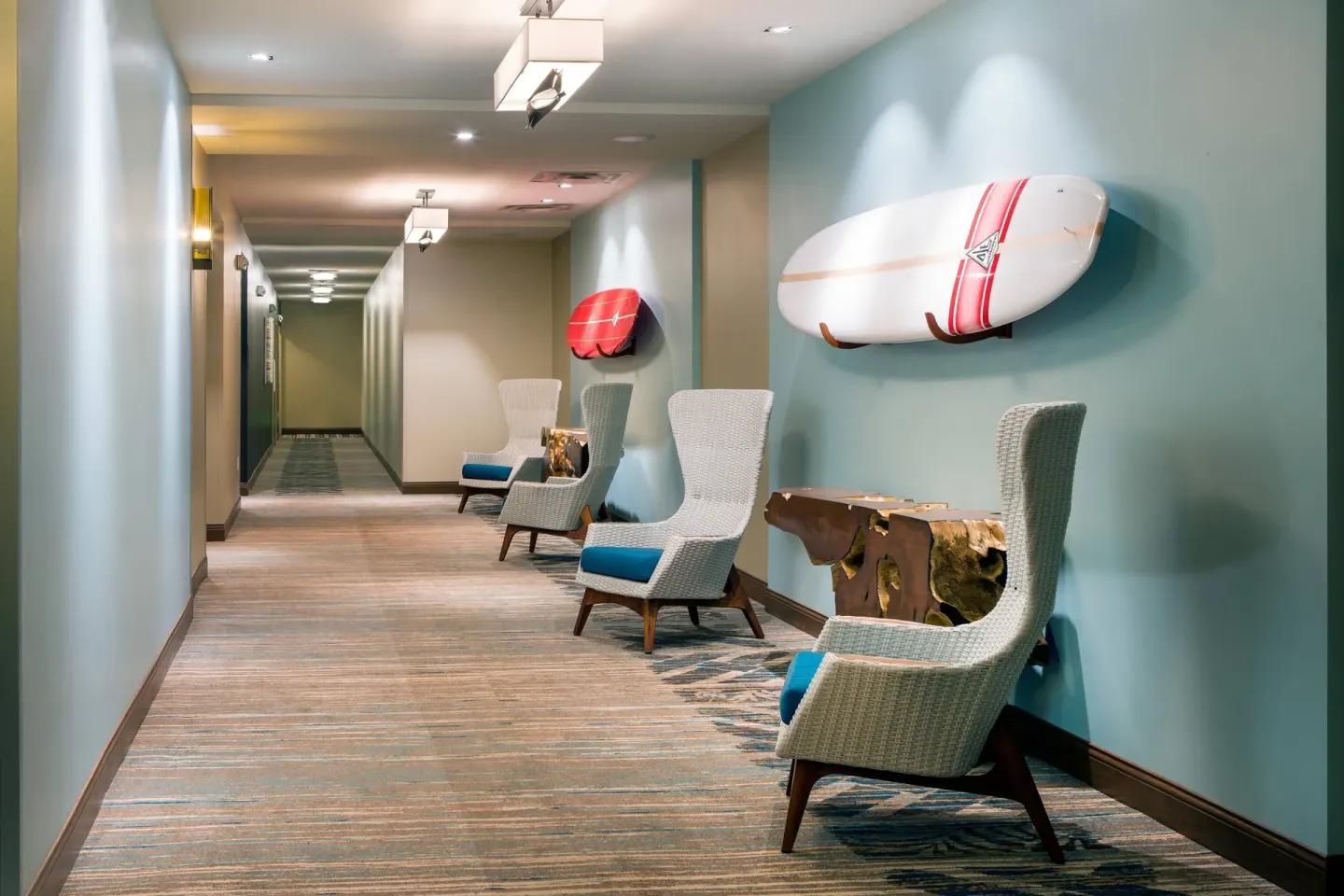 Resort hallway with lounge chairs and surfboard wall decor at Residence Inn Maui Wailea.