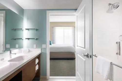 Accessible guest bathroom at Residence Inn Maui Wailea with long vanity, towel bars and bedroom doorway.