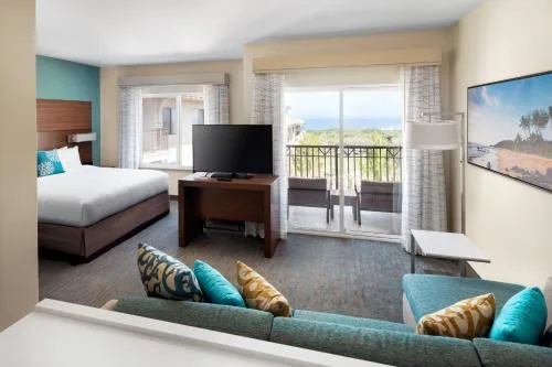 Studio ocean view room with bed, sofa, TV, and balcony at Residence Inn Maui Wailea.