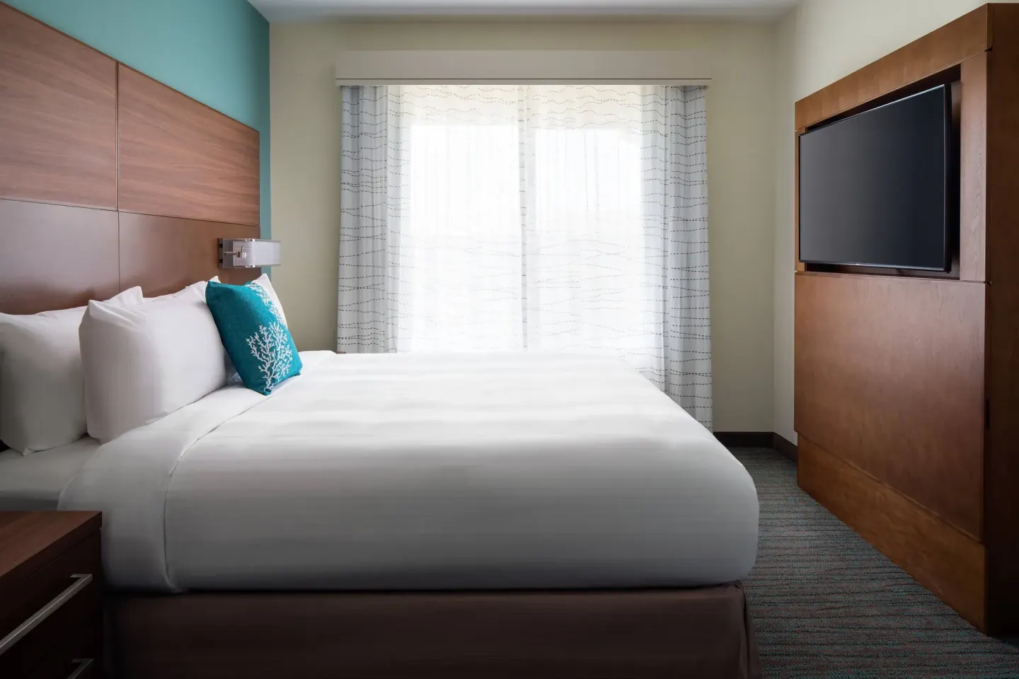 One-bedroom suite bedroom at Residence Inn Maui Wailea with one bed, window, and wall-mounted TV.