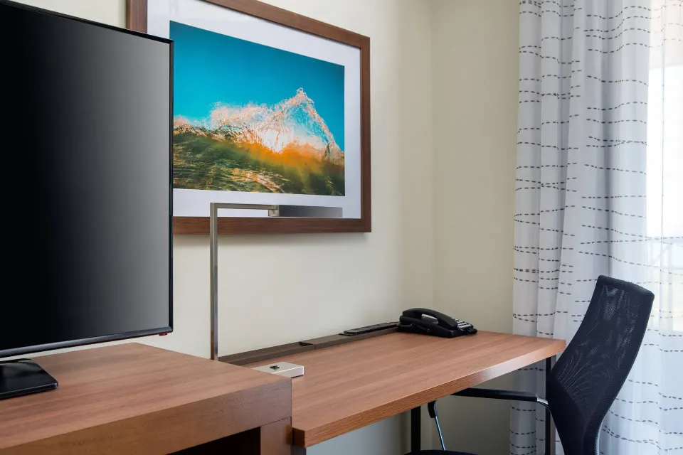 Guest room work desk at Residence Inn Maui Wailea with TV, chair, phone, and wave artwork.