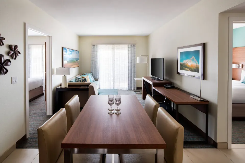 One-bedroom suite dining table, living area, and bedroom doorways at Residence Inn Maui Wailea.