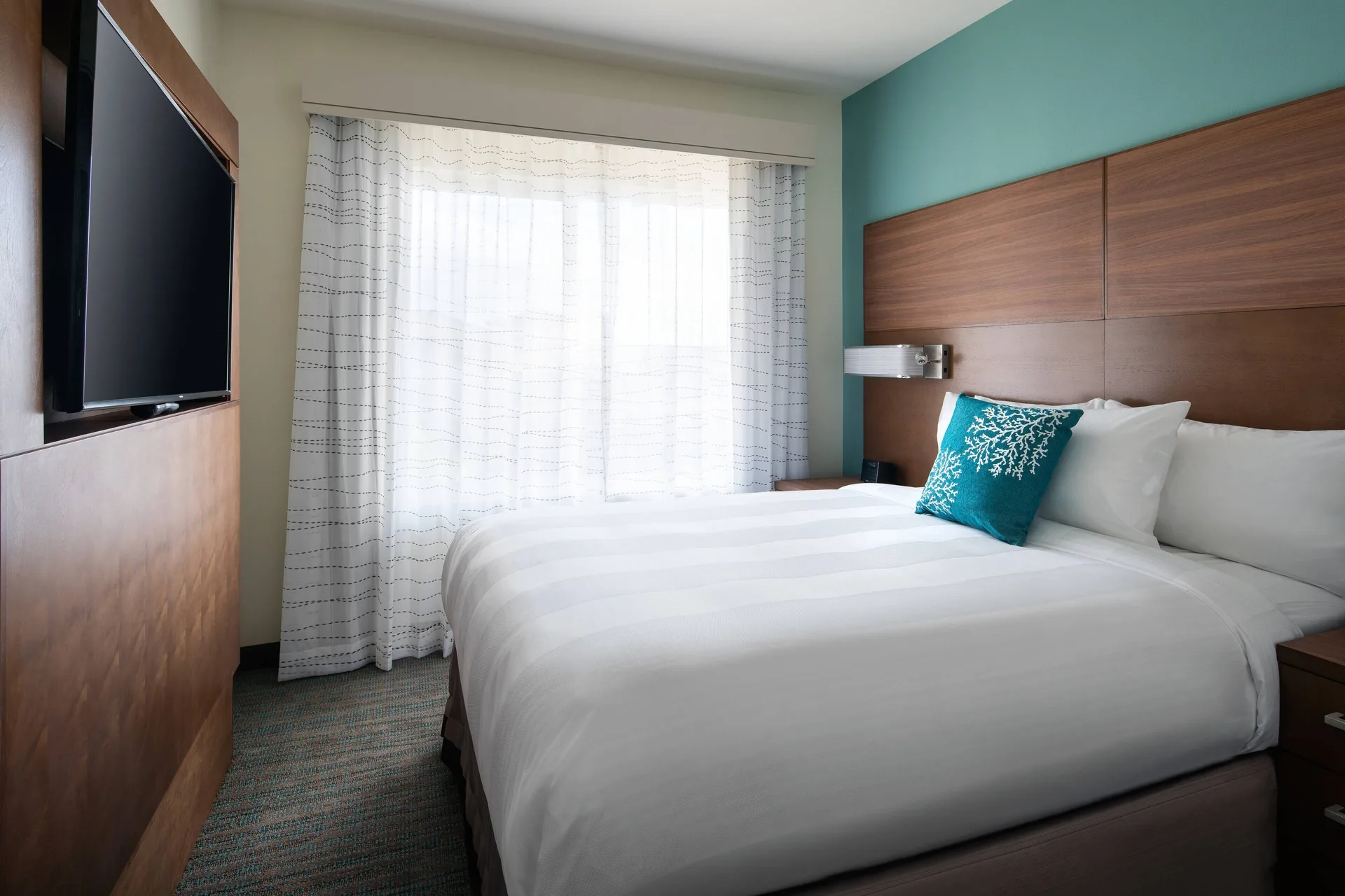 Two-bedroom suite bedroom with a king bed and wall-mounted TV at Residence Inn Maui Wailea.