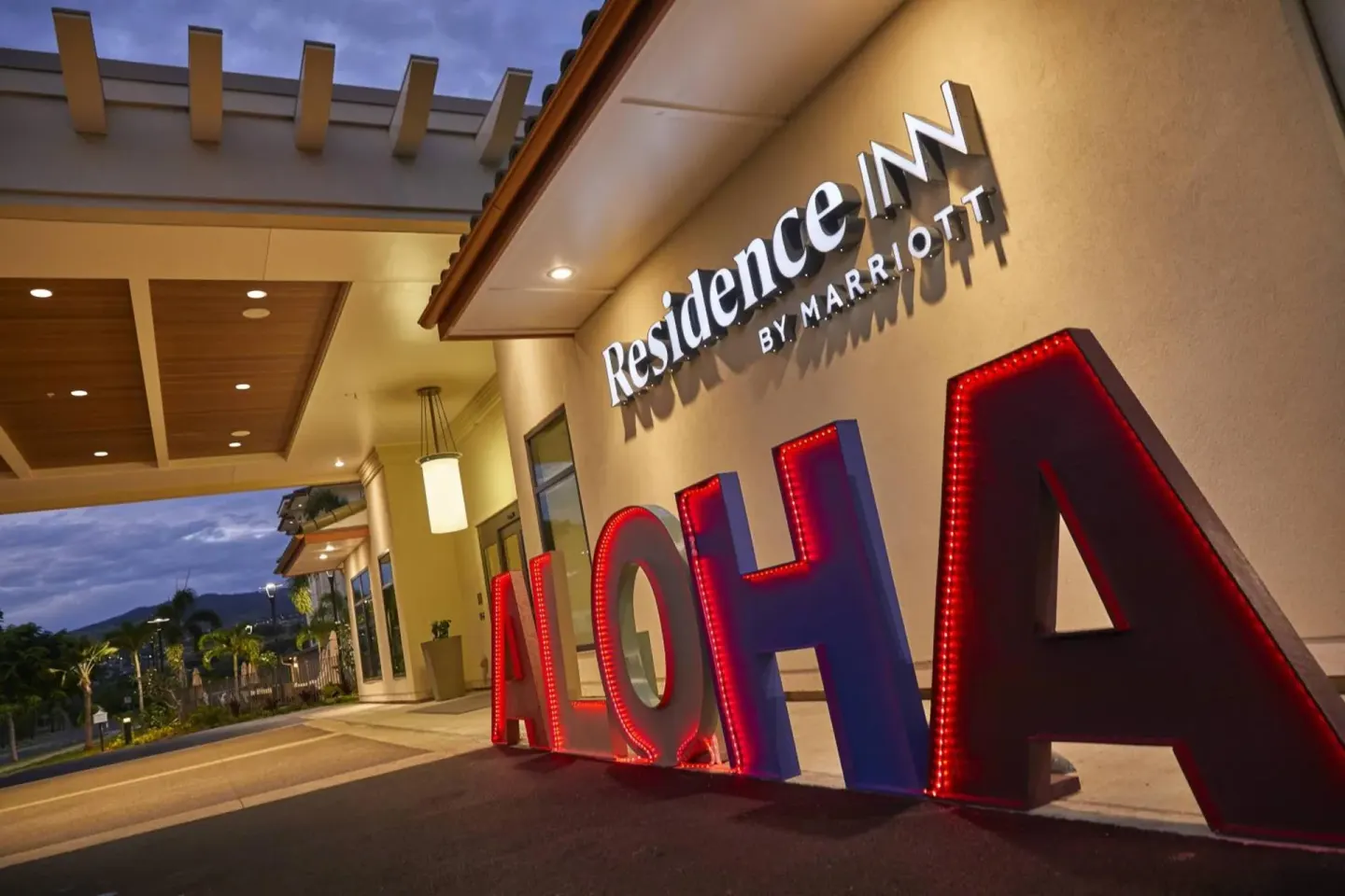 Evening hotel entrance with illuminated ALOHA letters at Residence Inn Oahu Kapolei.