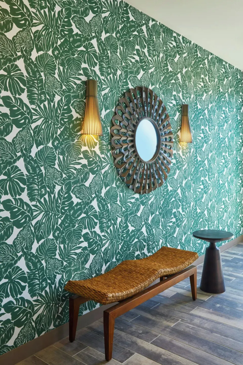 Lobby wall detail at Residence Inn Oahu Kapolei with green tropical wallpaper, mirror, bench, and sconces.