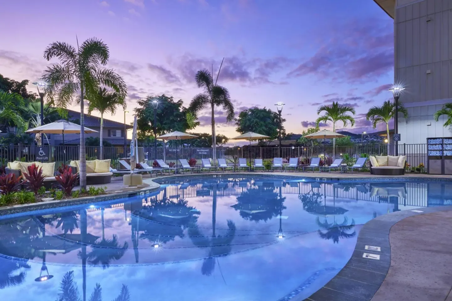 Outdoor pool with palms and lounge chairs at dusk at Residence Inn Oahu Kapolei.