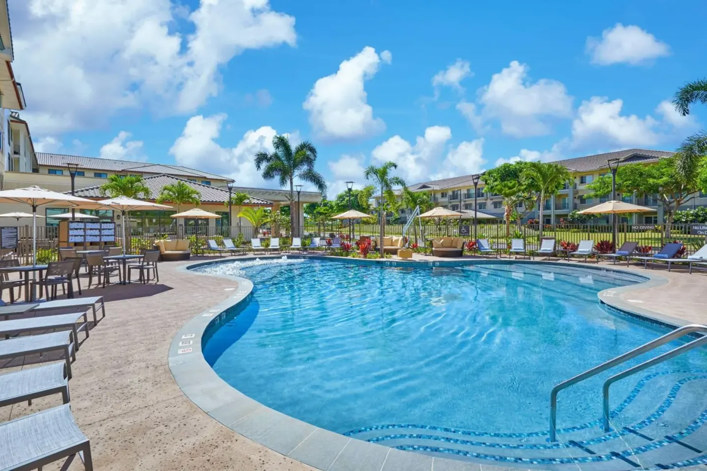Outdoor pool with lounge chairs and umbrellas at Residence Inn Oahu Kapolei.
