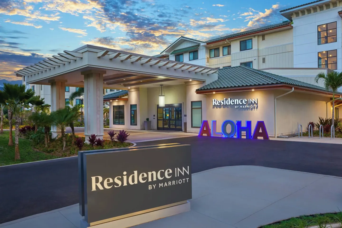 Entrance canopy and illuminated aloha sign at Residence Inn Oahu Kapolei at dusk.
