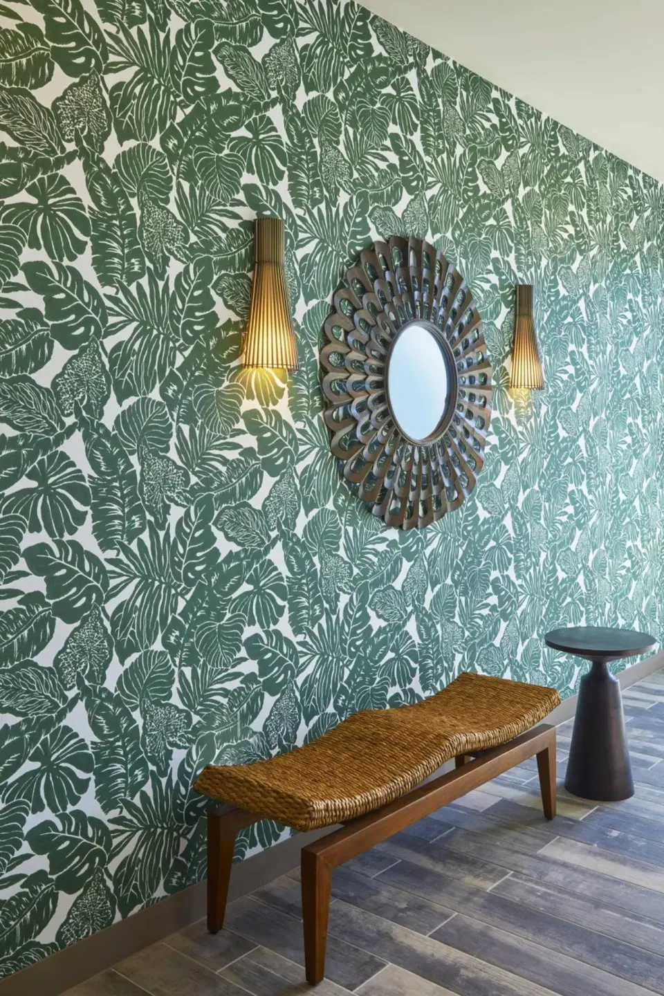 Tropical wallpaper, round mirror, bench, and side table at Residence Inn Oahu Kapolei.
