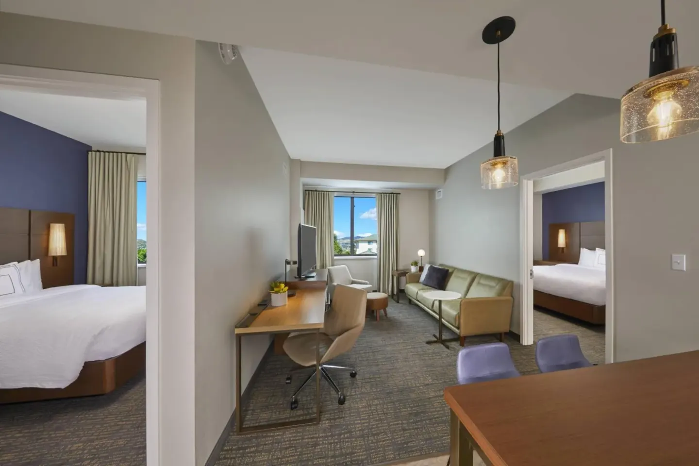 Suite living area between two bedrooms with work desk and sofa at Residence Inn Oahu Kapolei.