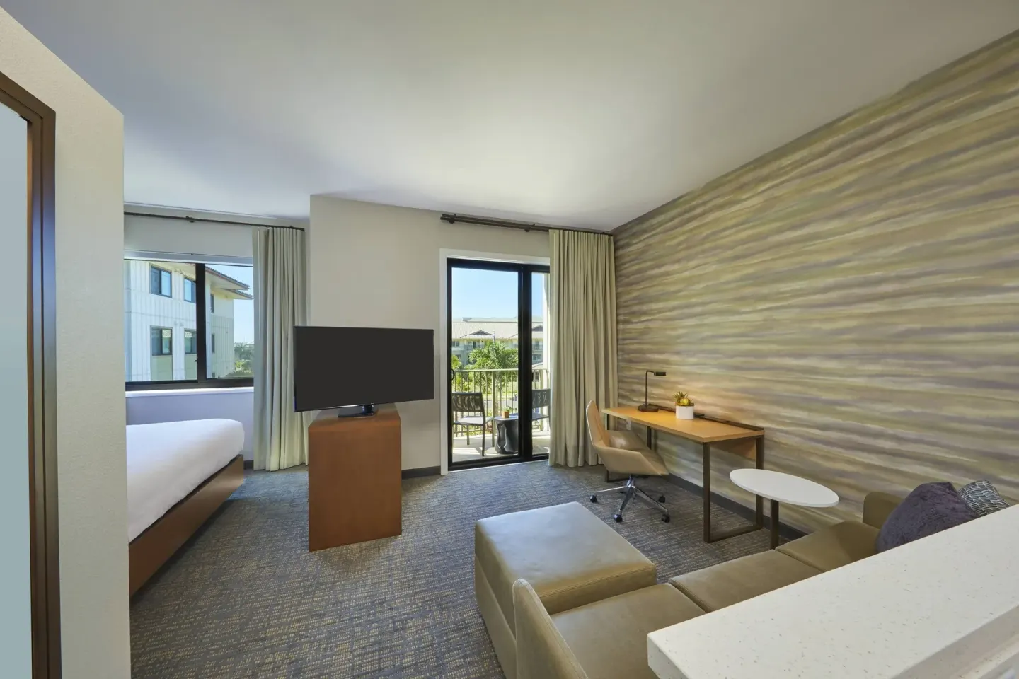 Studio balcony guest room with bed, sofa, desk, TV, and balcony at Residence Inn Oahu Kapolei.