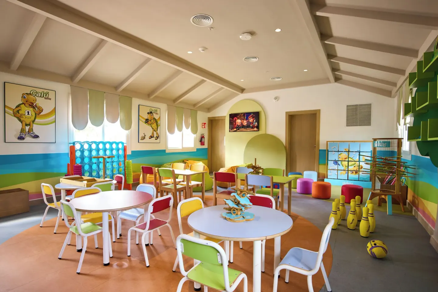 Children's playroom with colorful tables, chairs, games and wall art at Riu Negril.