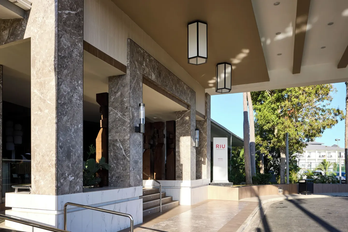 Covered entrance walkway with stone columns and signage at Riu Negril.
