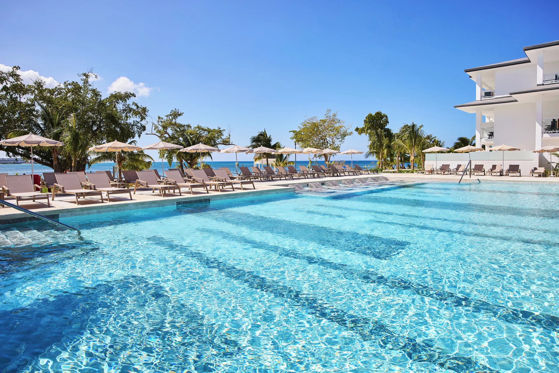 Main pool with loungers, umbrellas, and ocean beyond at Riu Negril.