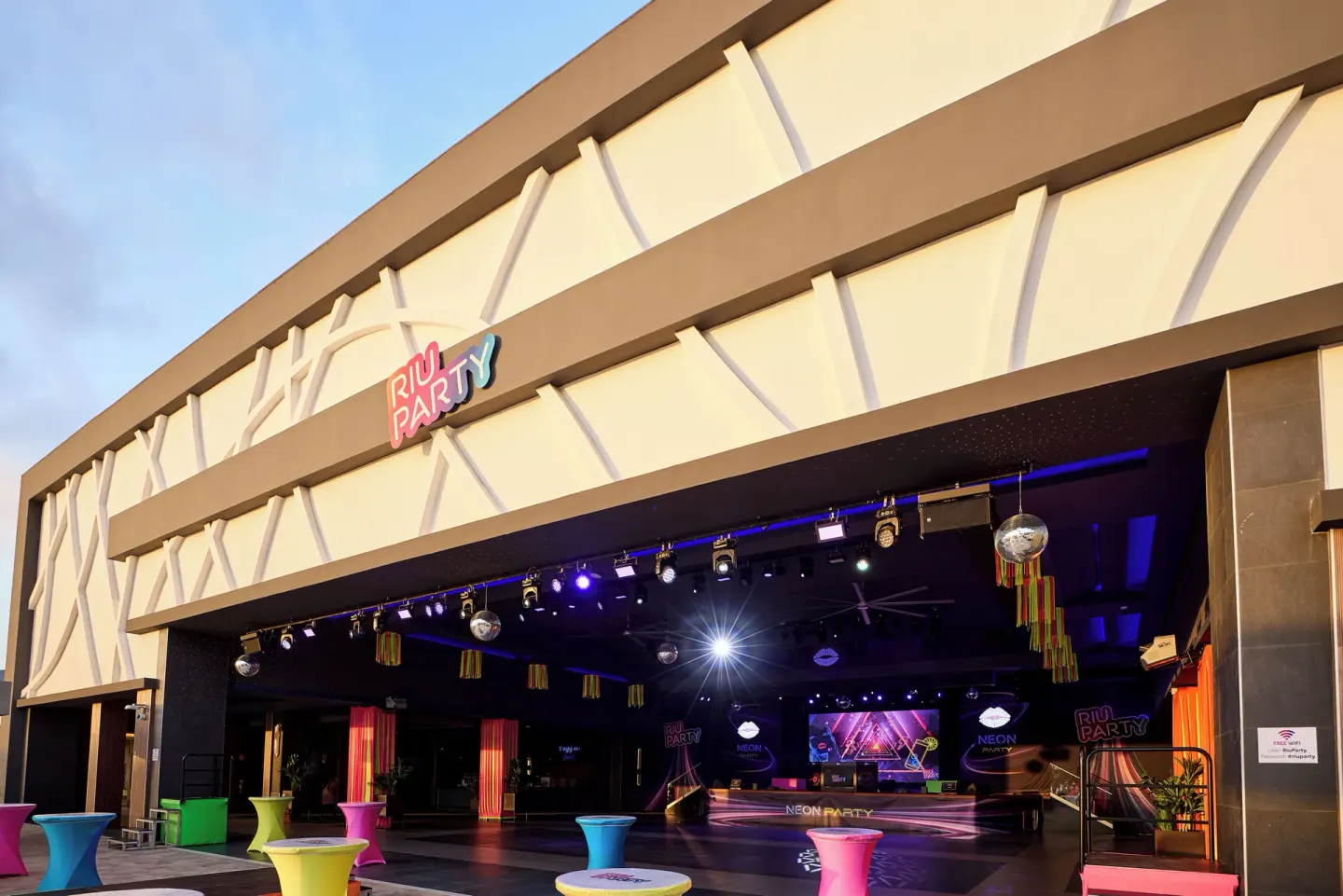 Outdoor party stage with colored cocktail tables and lights at Riu Negril.