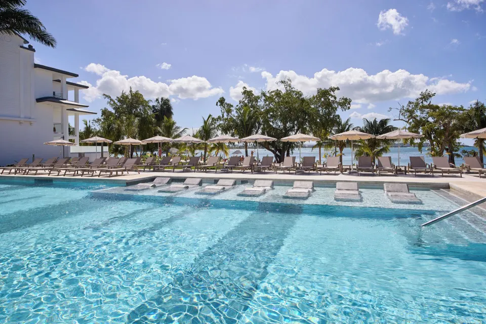 Pool with submerged loungers and shaded deck seating at Riu Negril.