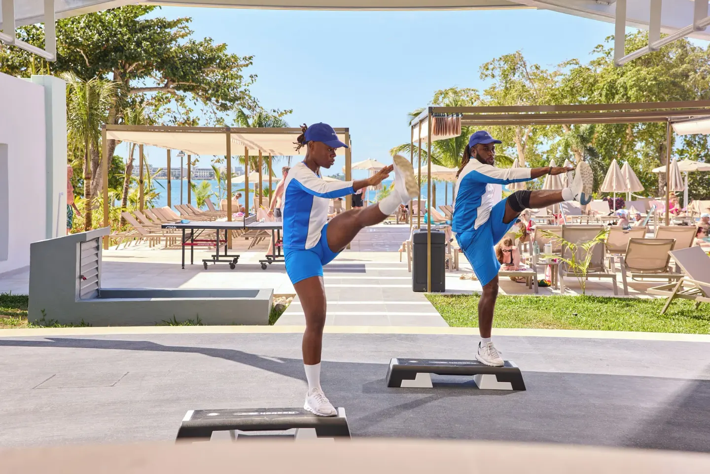 Fitness instructors perform high kicks on step platforms at Riu Negril.