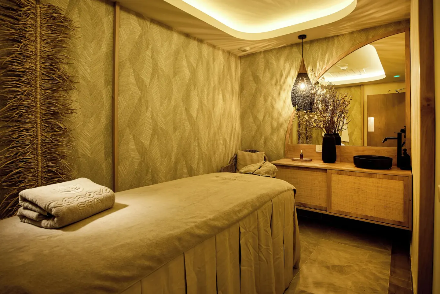 Spa treatment room with massage table, towels, sink, and pendant light at Riu Negril.