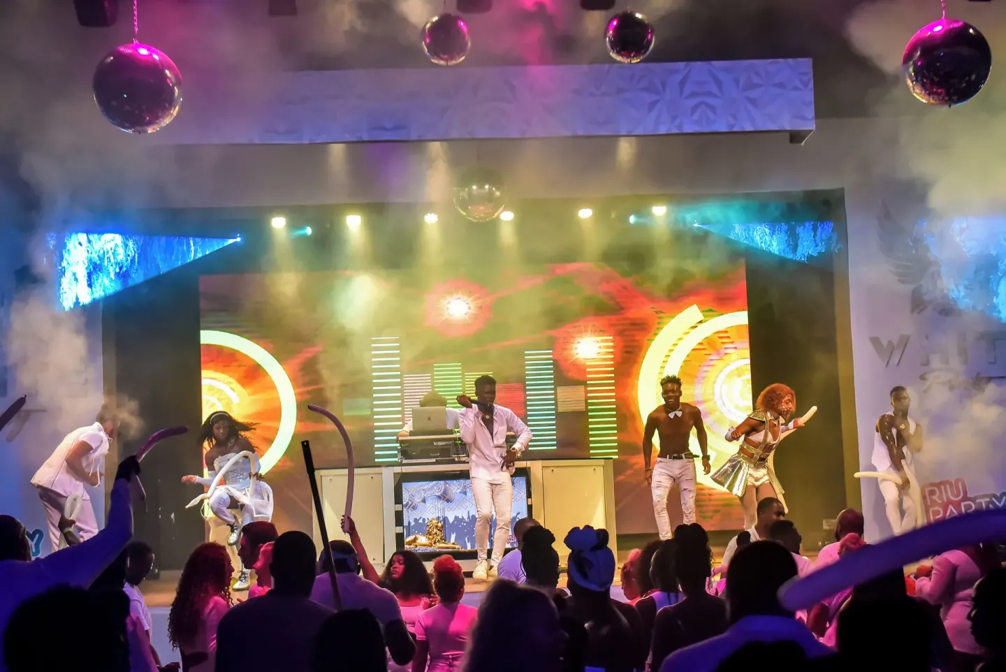 Performers dance on a colorful stage with smoke effects at Riu Negril.