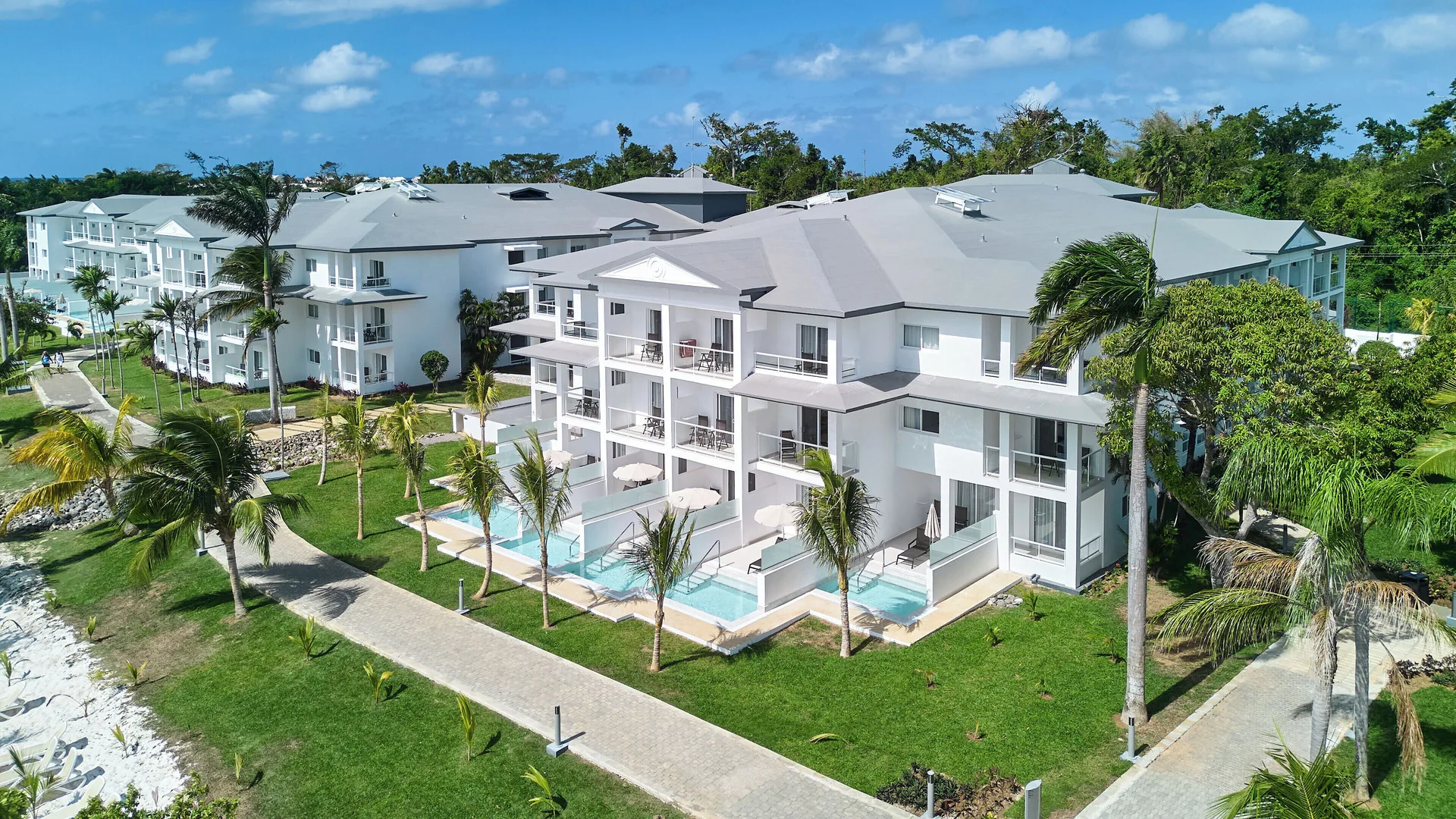 White guest buildings with swim-up terraces and palms at Riu Negril.