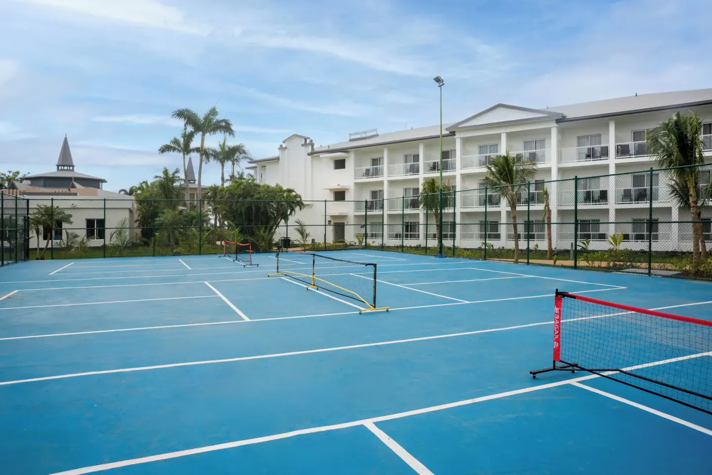 Blue tennis and pickleball courts beside resort buildings at Riu Negril.