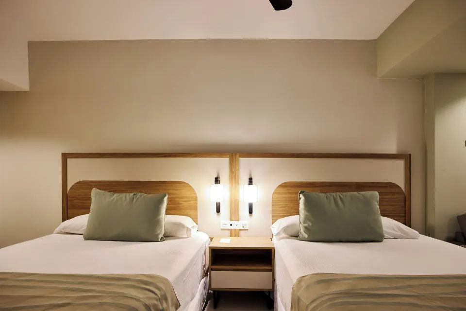 Two beds with wood headboards in a Family Room at Riu Negril.