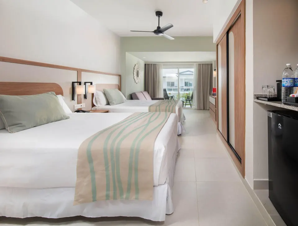 Room Garden View with two beds, balcony doors, and minibar area at Riu Negril.