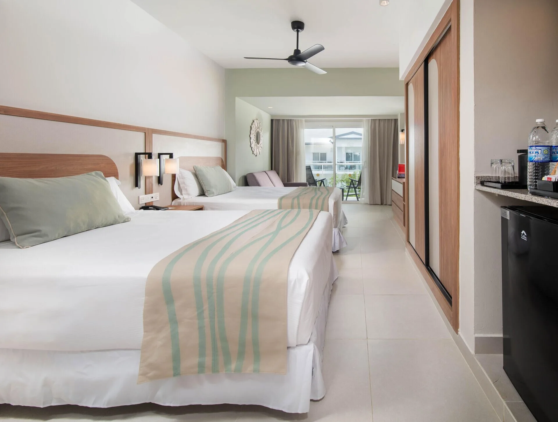 Room Garden View with two beds, balcony doors, and minibar area at Riu Negril.
