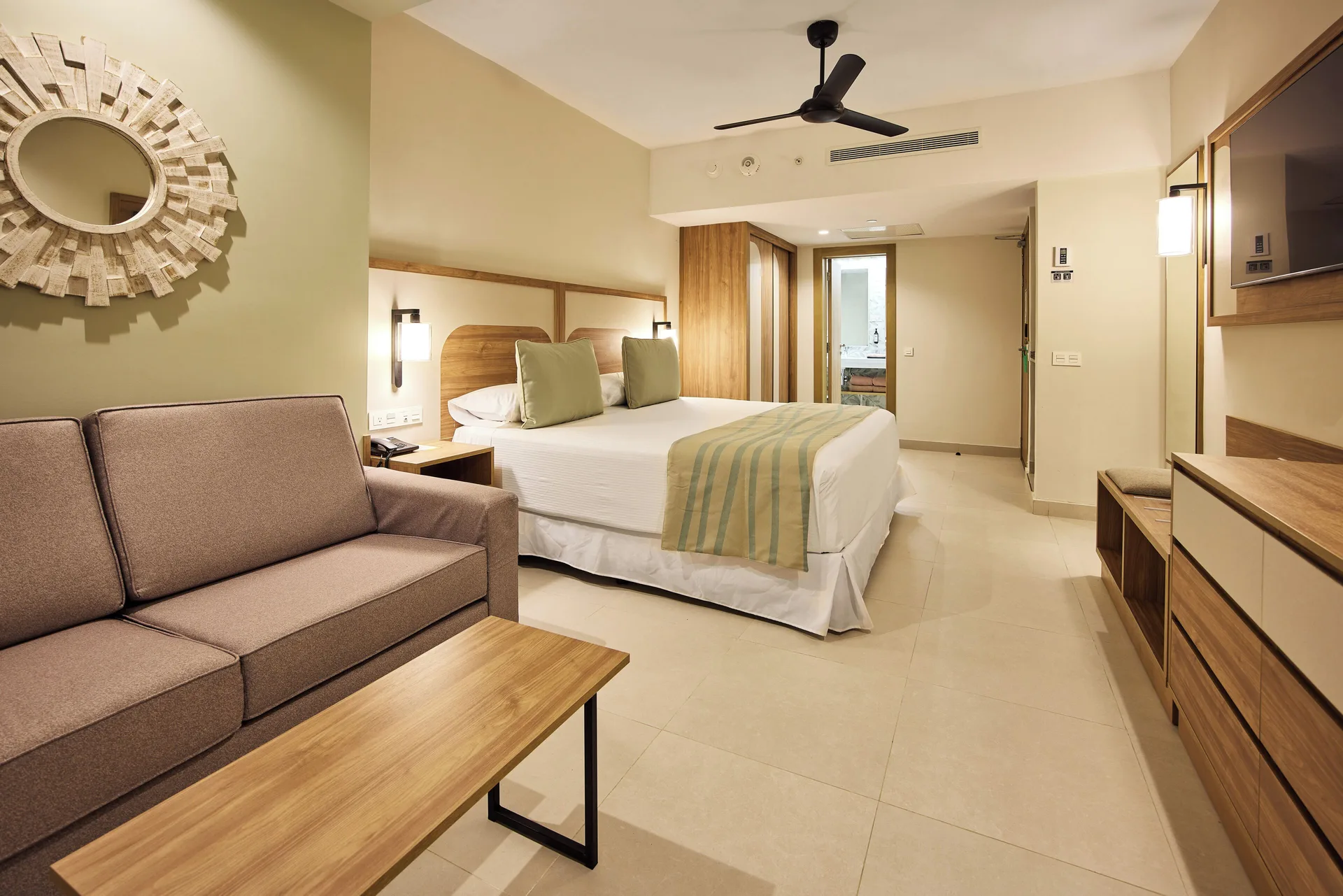 Room Oceanfront Swim-Up bedroom with sofa and wood furnishings at Riu Negril.