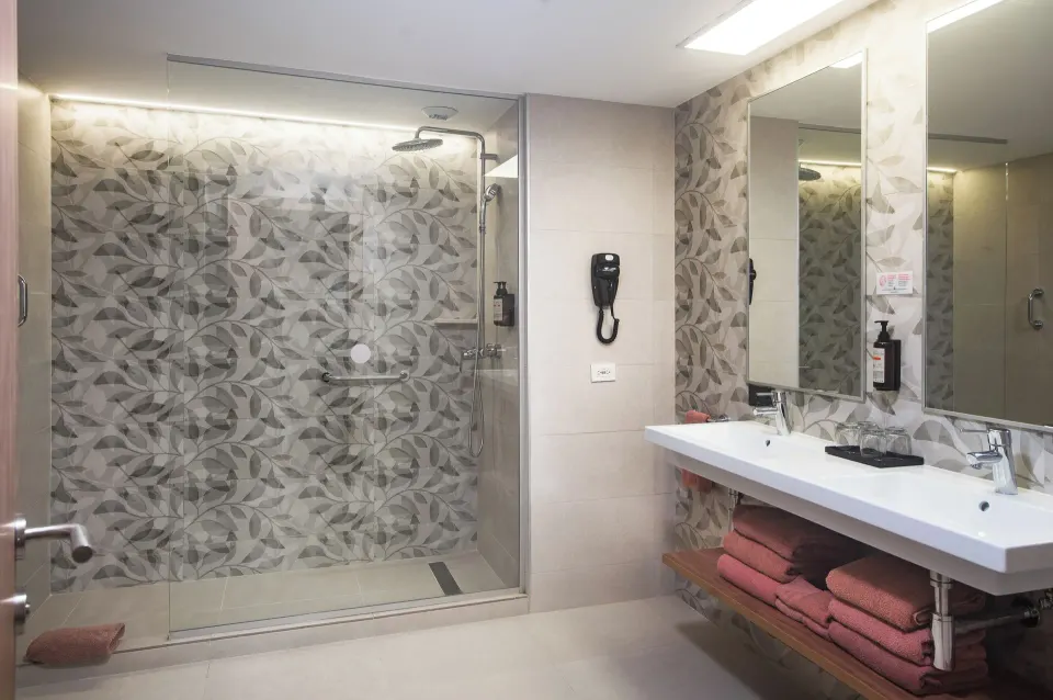 Guest room bathroom with glass shower and double sink at Riu Negril.