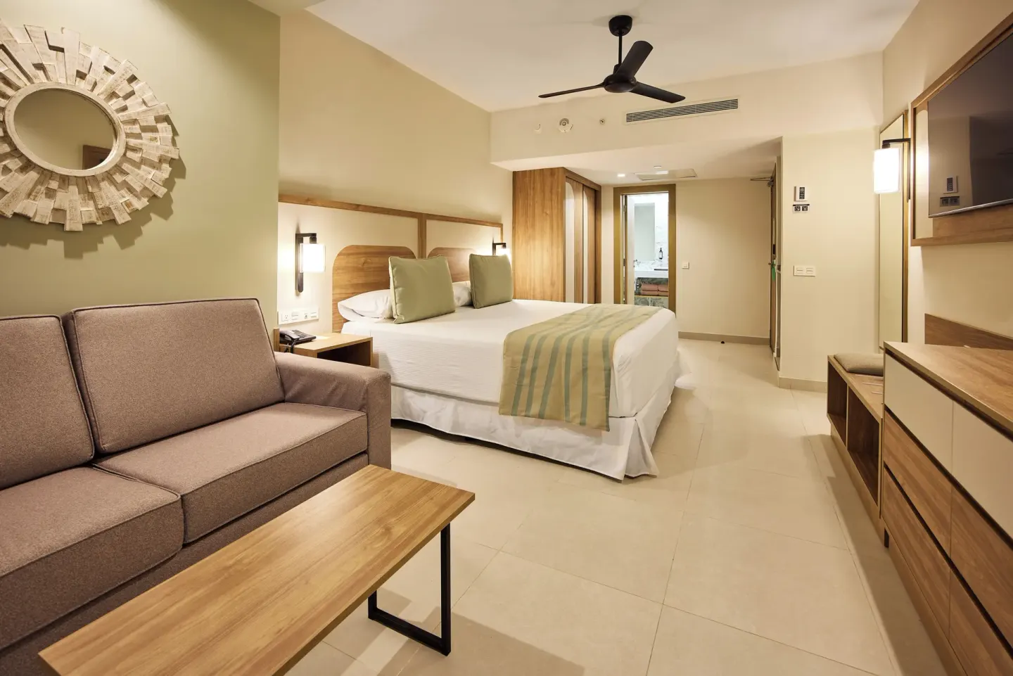 King bed guest room with sofa, coffee table, and dresser at Riu Negril.