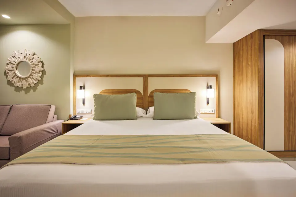 King bed with sofa and wood wardrobe in a guest room at Riu Negril.