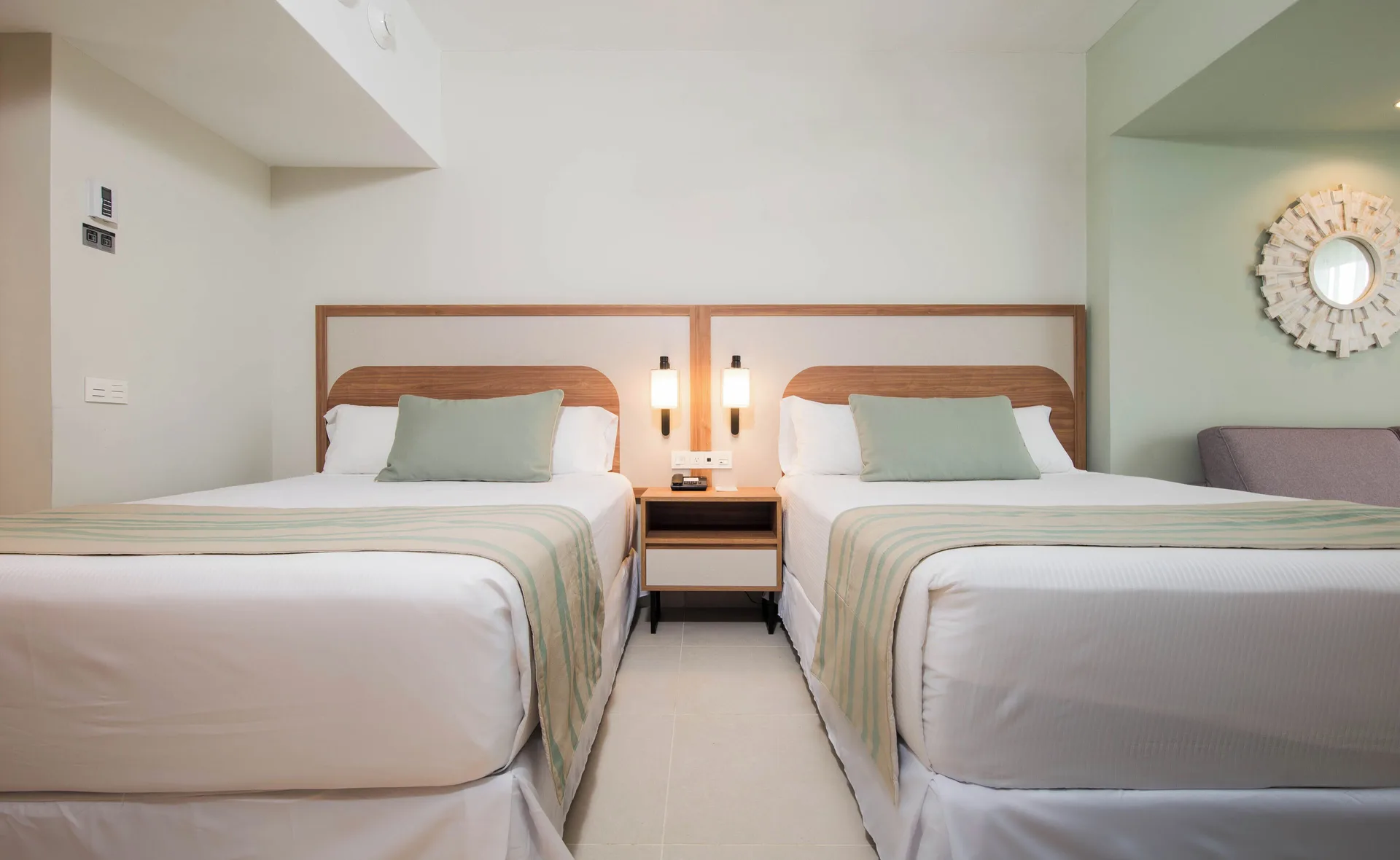 Two double beds with shared nightstand in a guest room at Riu Negril.