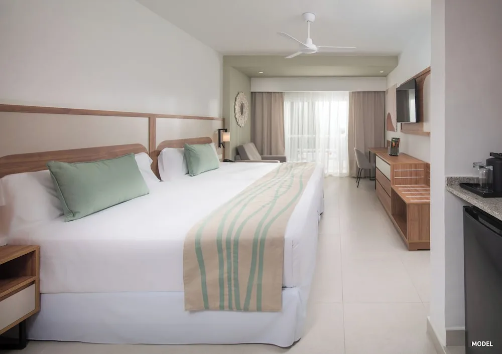 Standard room with two beds, balcony doors, desk and TV at Riu Negril.