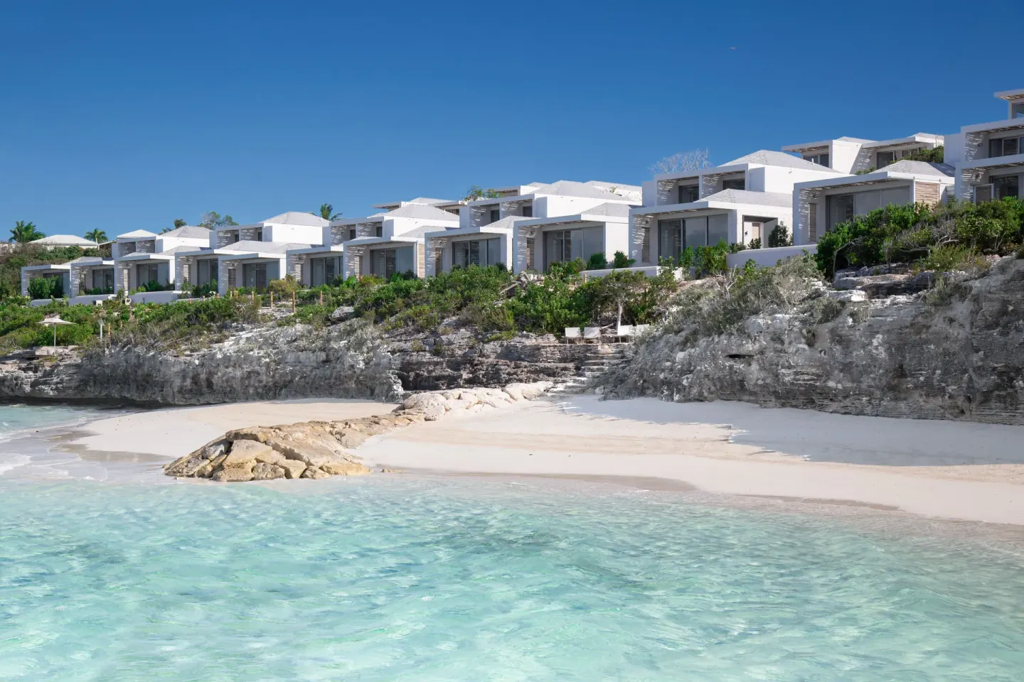 White villas above a sandy cove and clear water at Rock House.