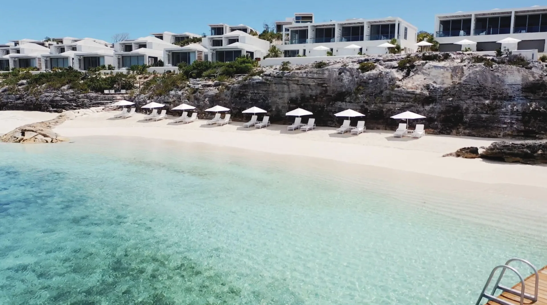 Beach loungers and umbrellas below cliffside villas at Rock House.