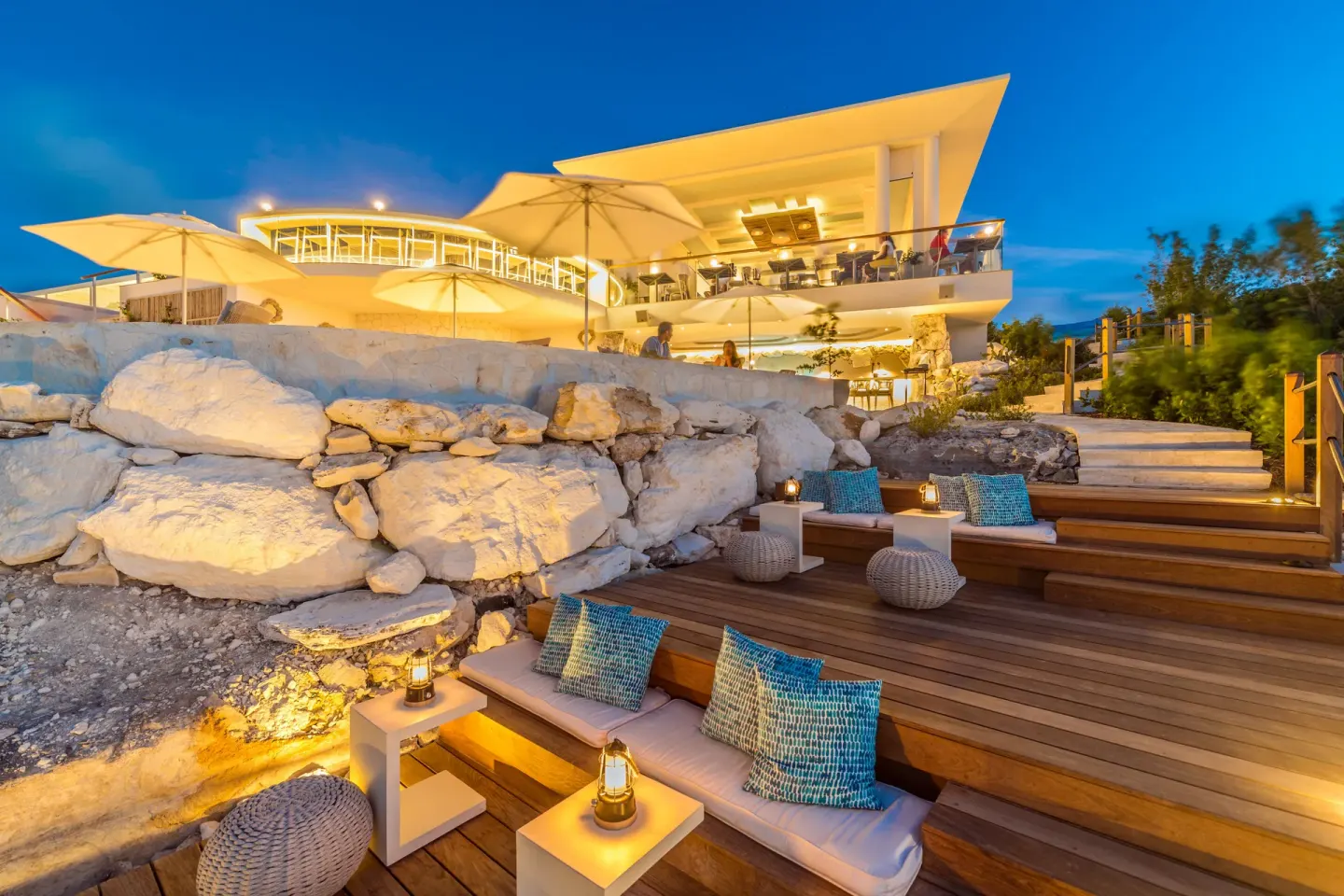 Lantern-lit cliffside lounge seating and resort building at dusk at Rock House.