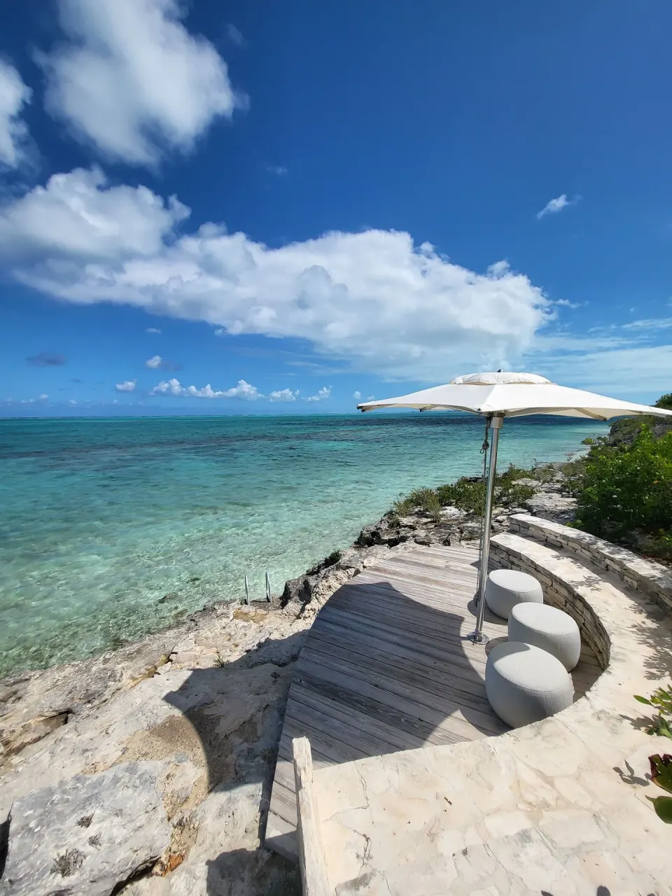 Clifftop deck with umbrella and turquoise sea at Rock House.