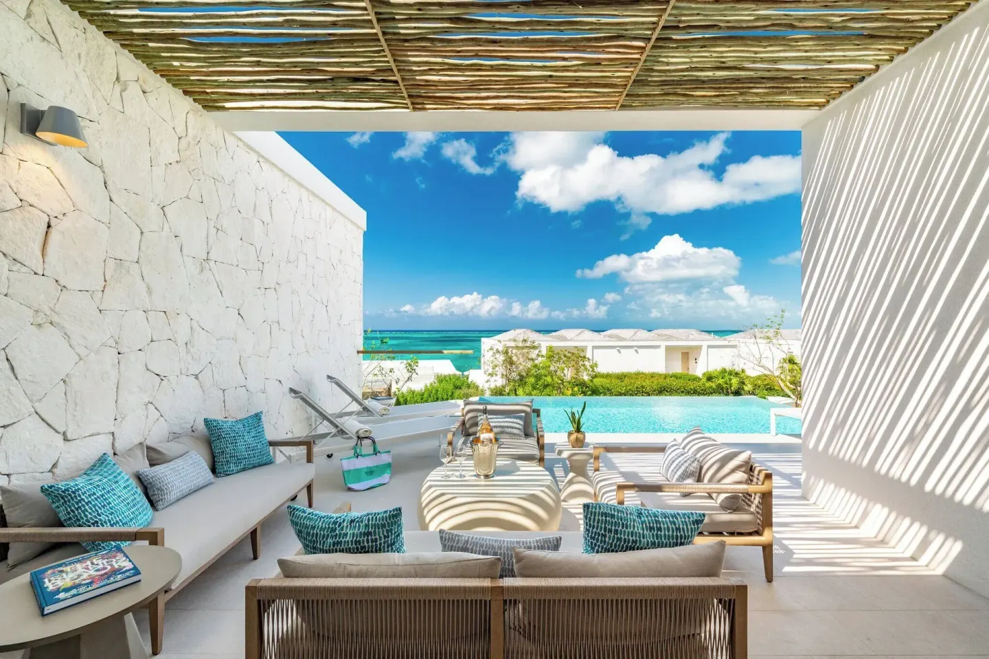 Covered pool terrace at Rock House with cushioned seating and a turquoise ocean view.