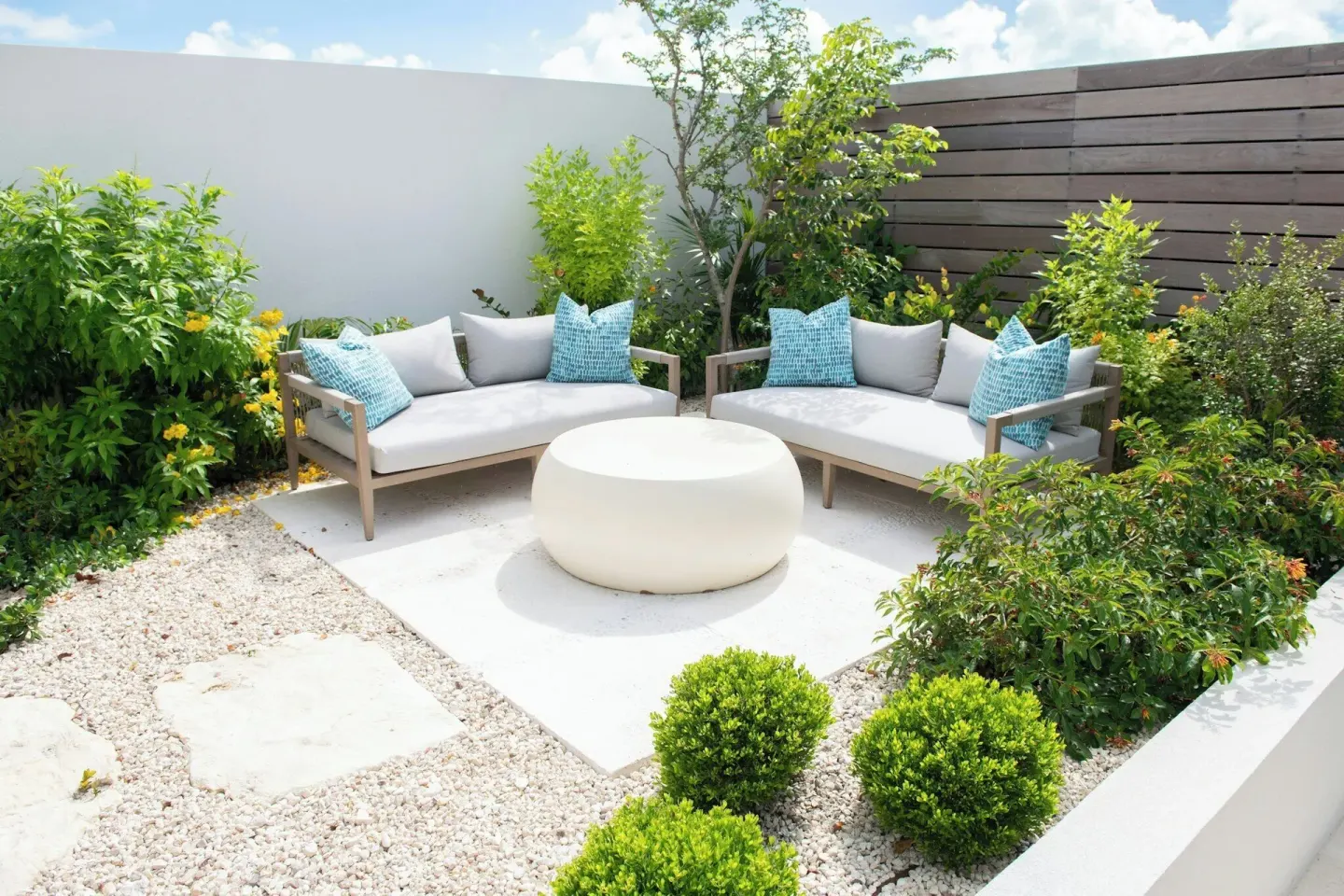 Garden patio seating with pale sofas and blue pillows at Rock House.