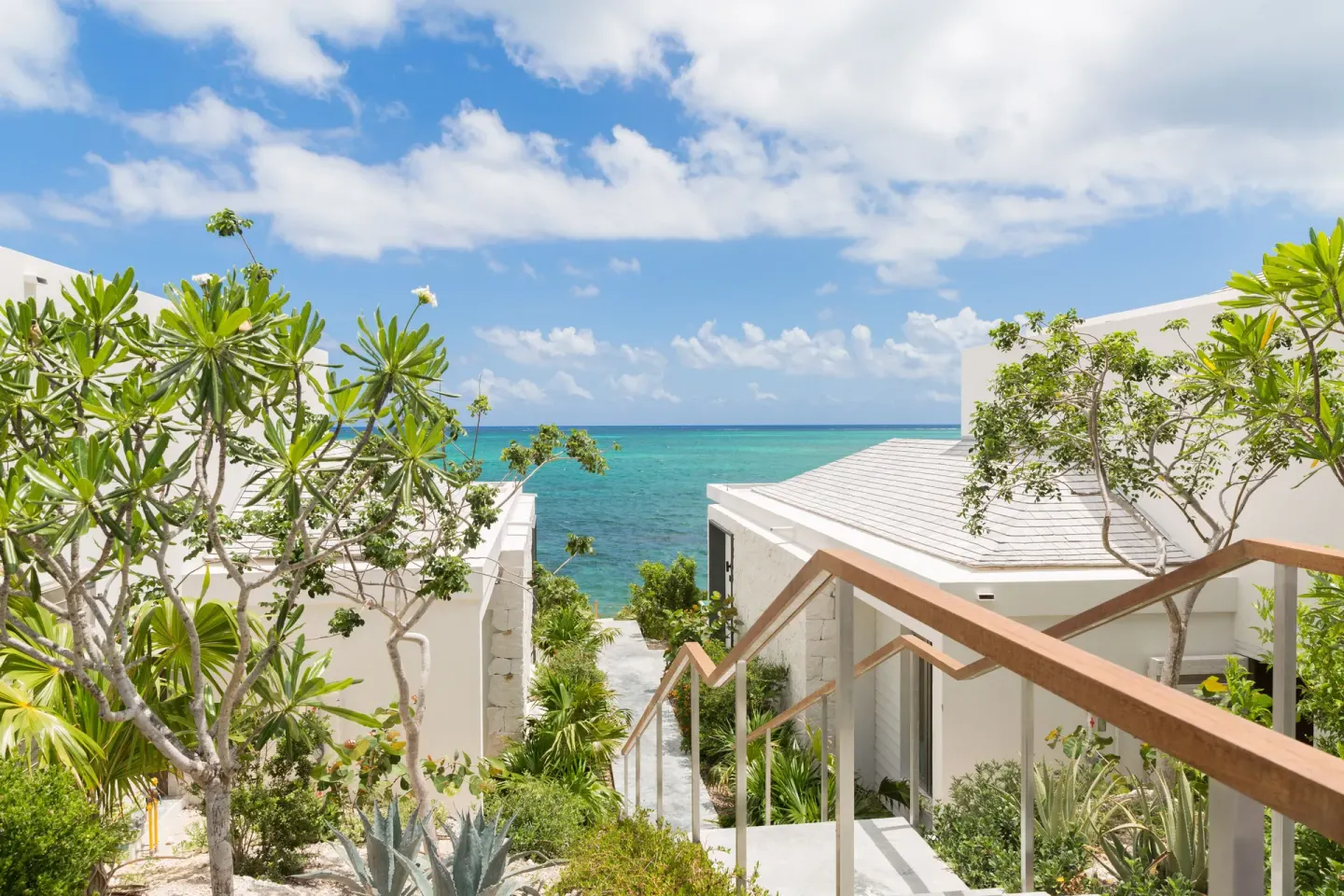 Garden stairway with ocean view between white buildings at Rock House.