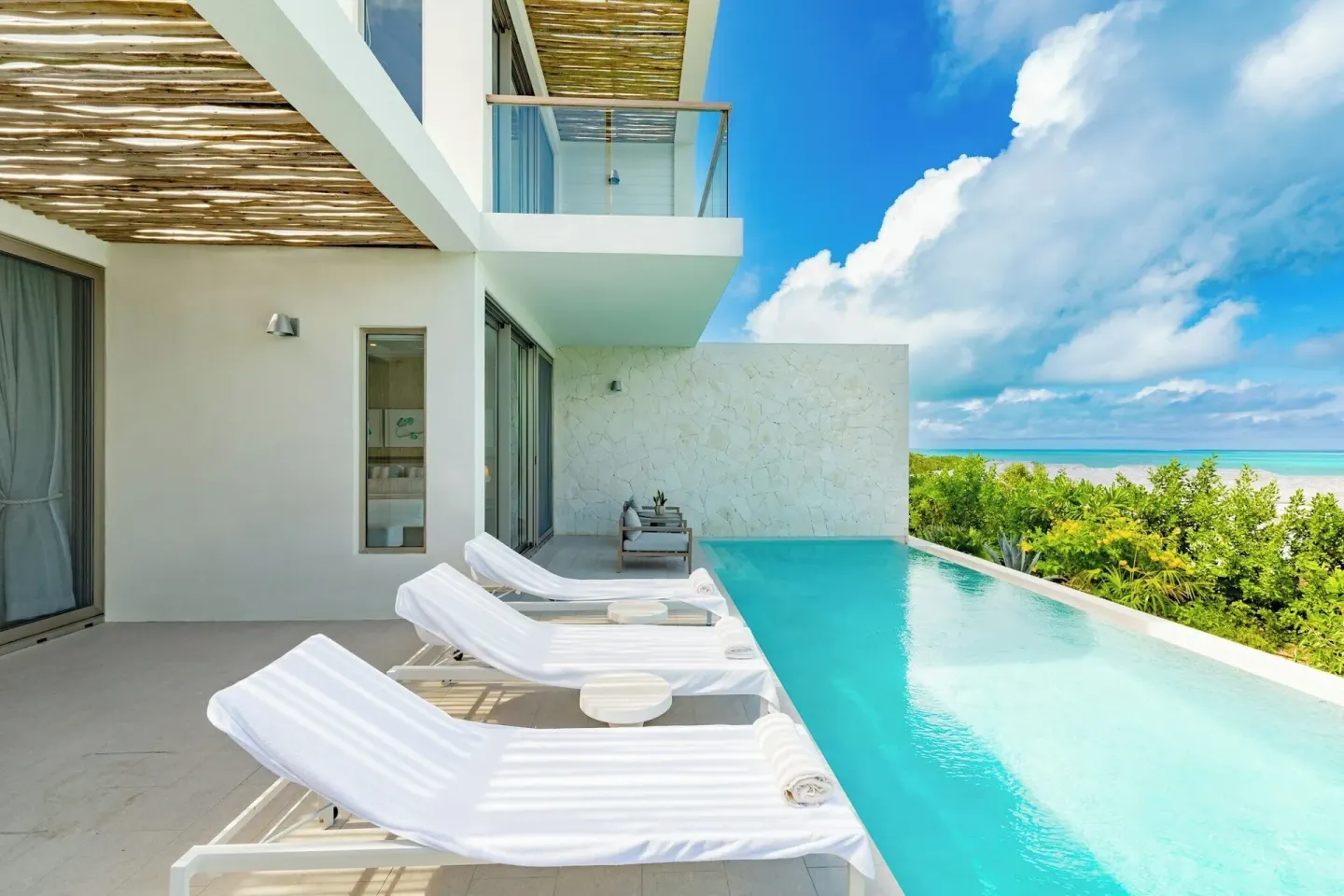 Infinity pool terrace at Rock House with white loungers and ocean views beside the suite.