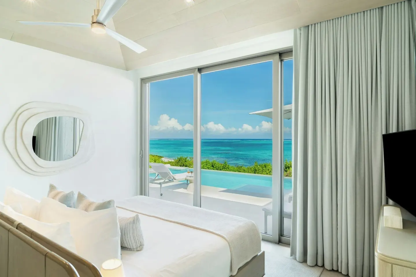 Guest room at Rock House with a bed, sliding glass doors, pool terrace, and ocean view.