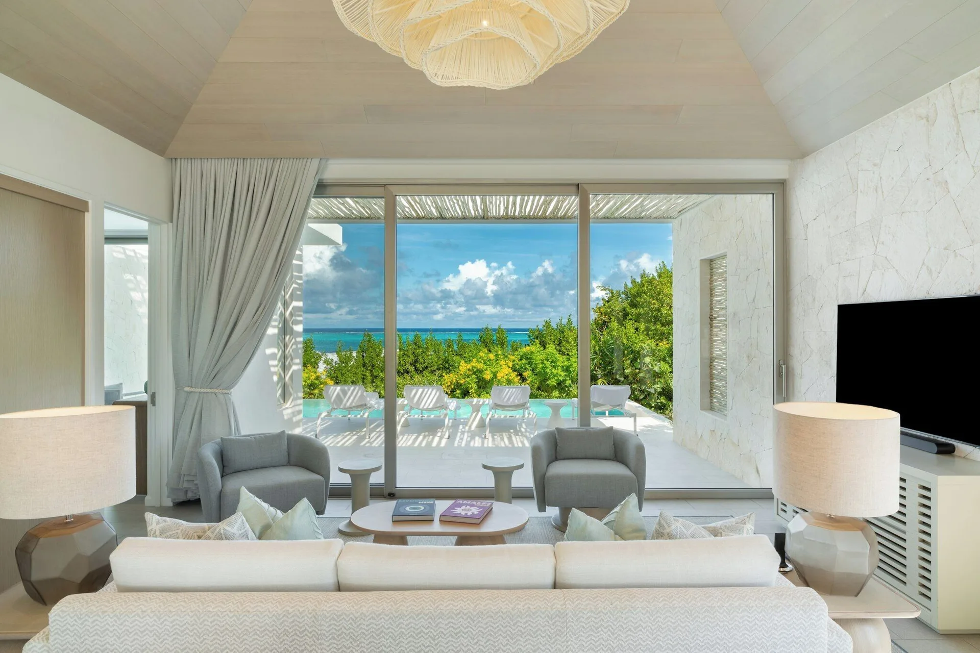 Living room at Rock House with sofas, lounge chairs, terrace seating, and ocean view.
