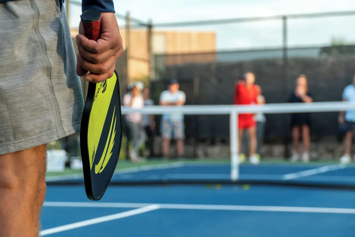 Pickleball player holding a paddle beside a blue court at Rock House.