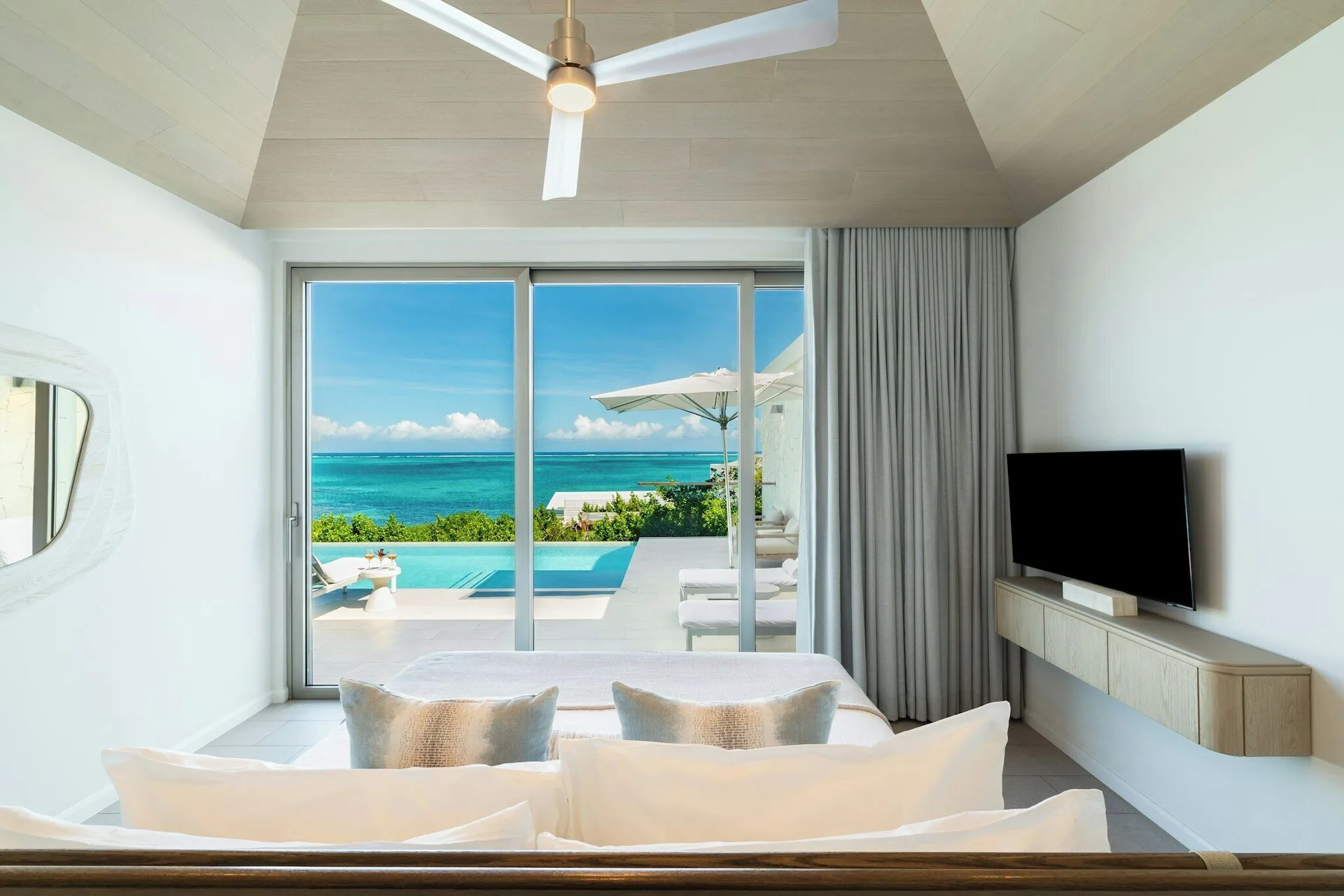 Guest room at Rock House with a bed facing a terrace, private pool, and blue ocean.