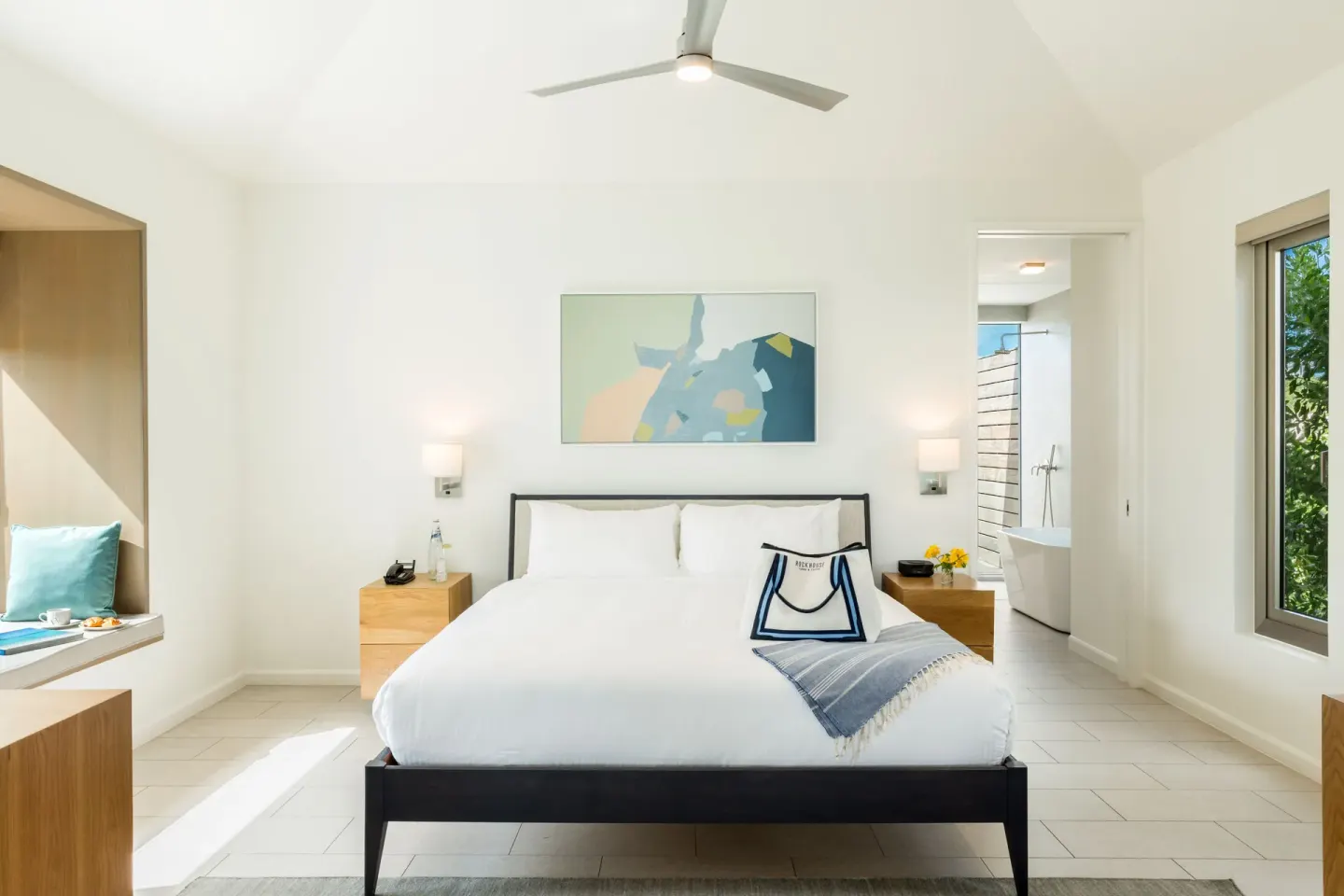 Ocean View Ridge One Bedroom at Rock House with king bed, artwork, and bright bathroom entry.