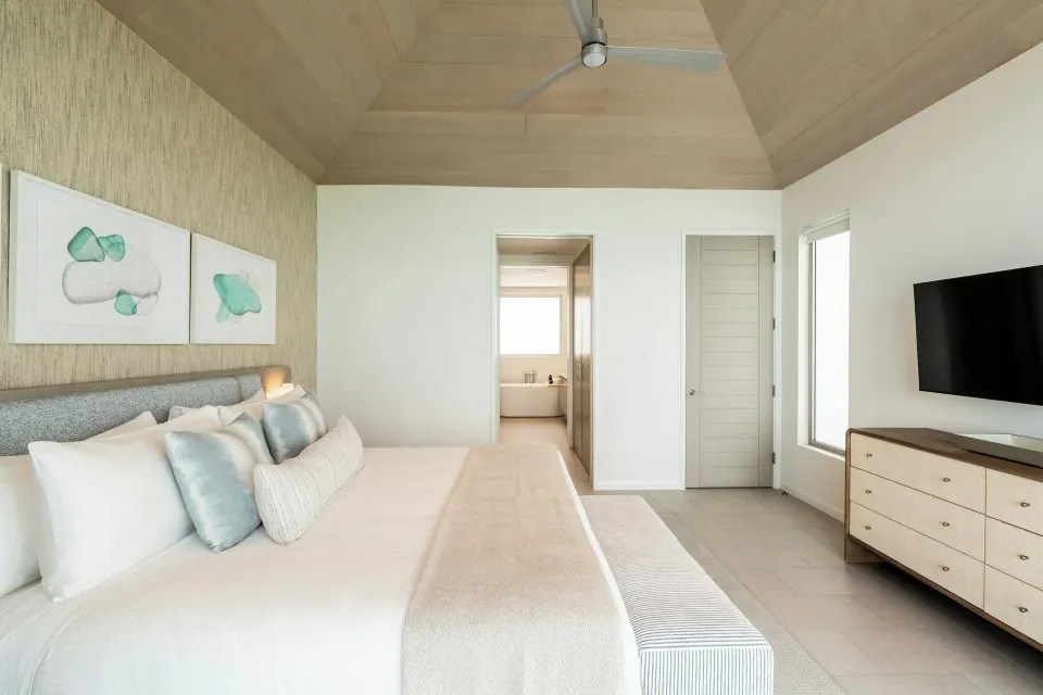 Ocean-view villa bedroom with king bed, TV, and bathroom doorway at Rock House.