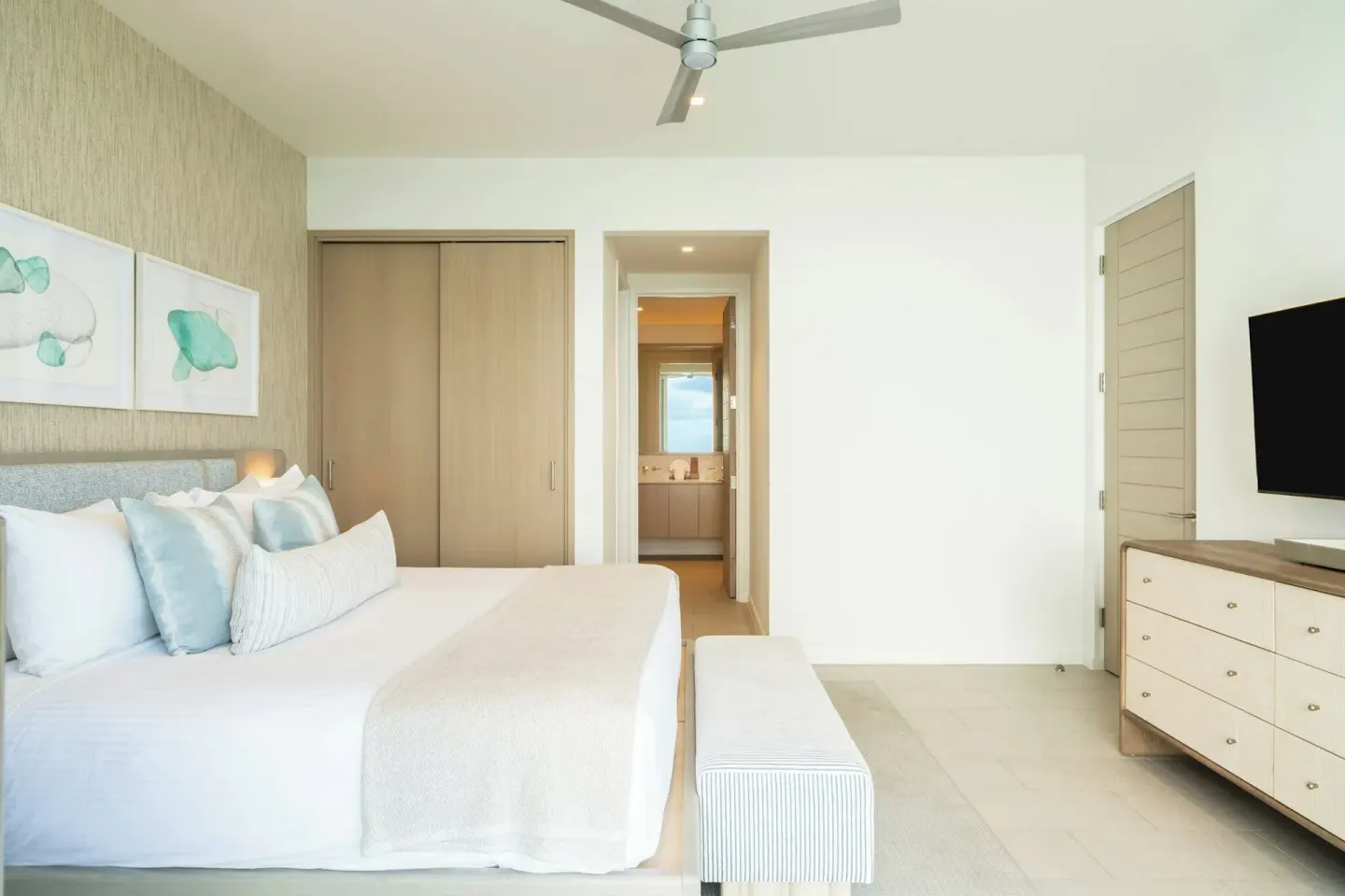 Ocean-view villa bedroom with king bed, closet, dresser, and bathroom view at Rock House.